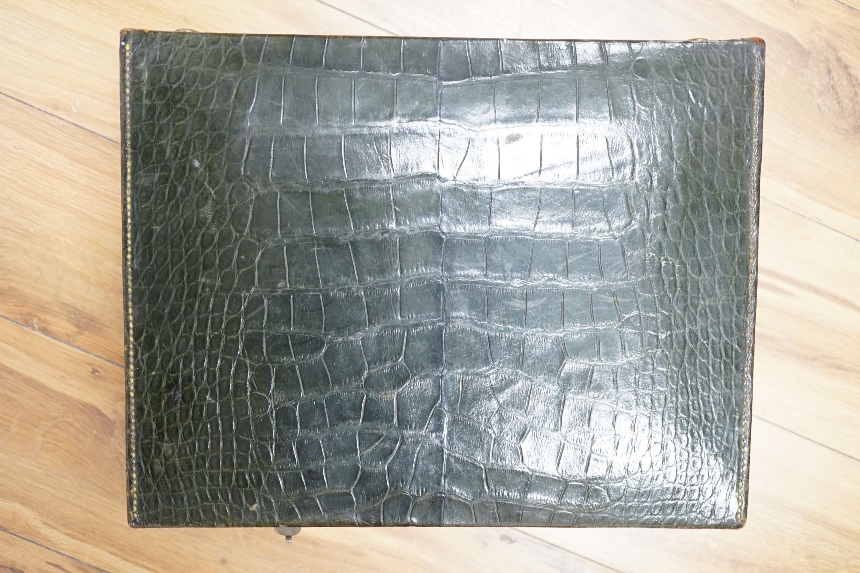 An early 20th century green crocodile toilet case with silver mounted interior, width 39 cms.